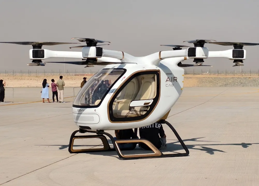 A futuristic aerial taxi with multiple rotors parked on an open landing area.